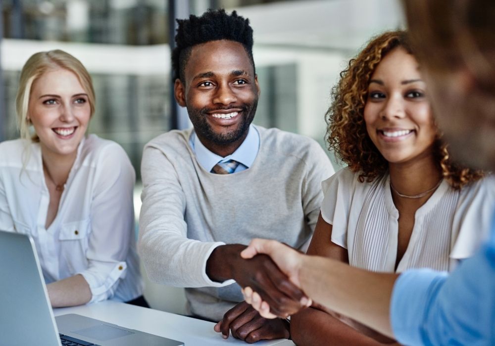 Business professionals meeting and shaking hands in a modern office setting, representing trust, due diligence and professional engagement within a South African firm with global reach.