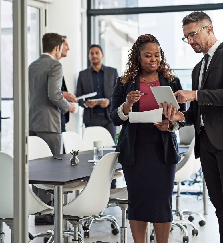 Business professionals reviewing documents in a formal meeting environment, reflecting collaborative analysis, due diligence and corporate investigative consultation.