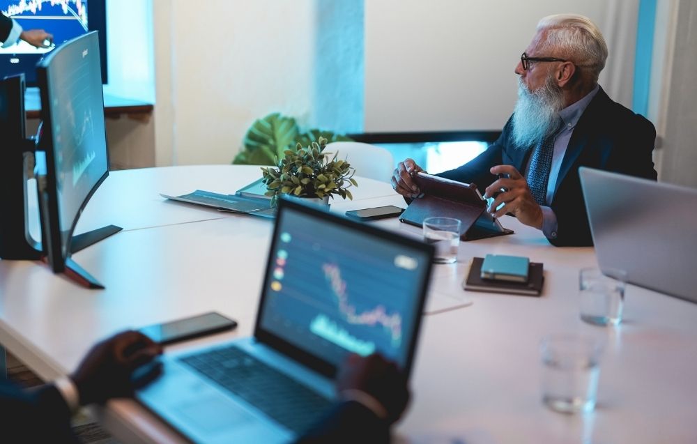 Senior professionals analysing digital data on secure devices during a strategic review, illustrating forensic computer services, digital evidence assessment and investigative oversight by Grudko Associates.